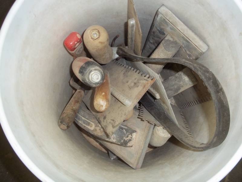lot 127 image: bucket of Cement  Masonary tools (hand sander, slotted trowels)
