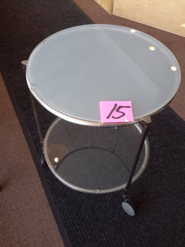 lot 15 image: Round Metal, Frosted Glass Side table on wheels.. Includes Magazine organizer and the magazines.