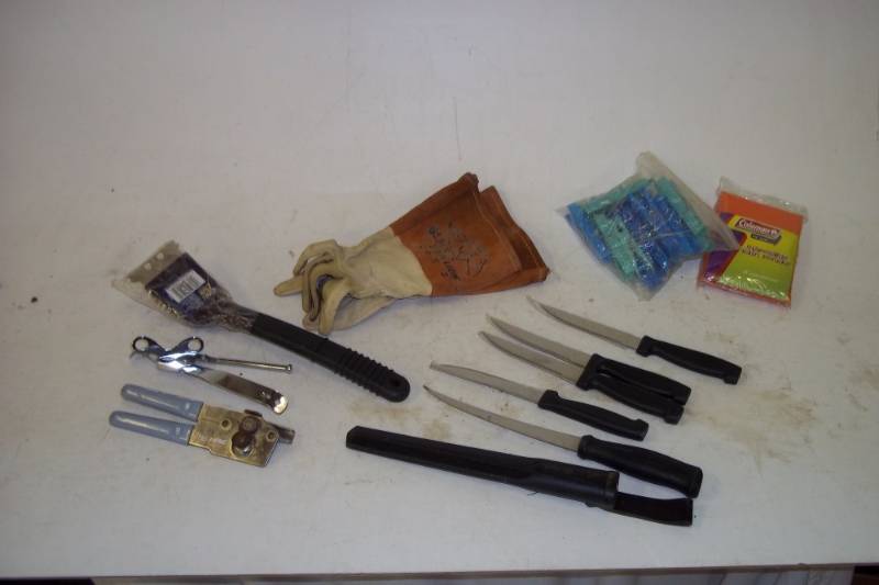 lot 16 image: Camping essentials. Leather grilling gloves, steak knives, can opener, rain poncho and clothes pins.