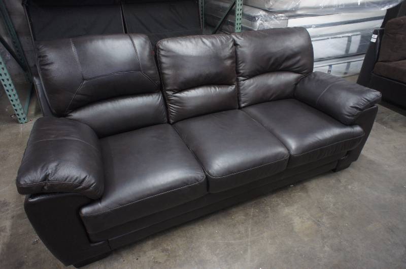 lot 17 image: 82 High End Brown Leather Sofa, has one mismatched cushion. Dimensions 82W X 35D X 32T