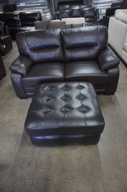 lot 24 image: 67 High End Dark Brown Leather Love-seat with Ottoman, some cosmetic damage to right cushion. Dimensions 67W X 35D X 32T. Ottoman 33X33X17