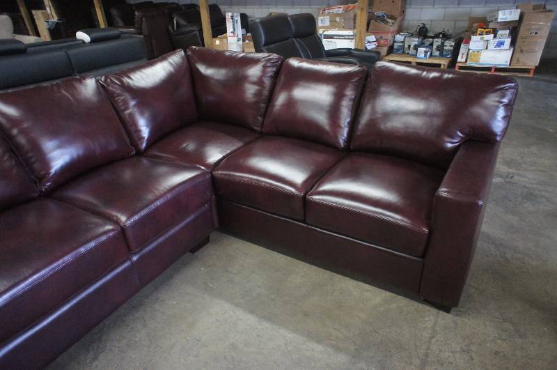 lot 27 image: 114 High End Reddish Leather Sectional, has one mismatched cushion. Dimensions 114W X 90D X 30T