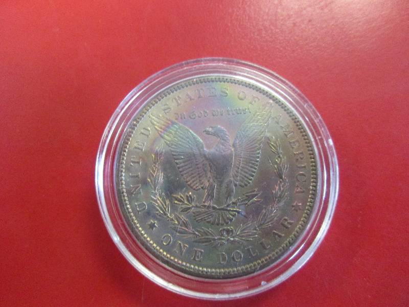 1897-P Morgan Silver Dollar in AU Condition in protective capsule. The Morgan shows toning on the upper left of the observe side and in center of the reverse.