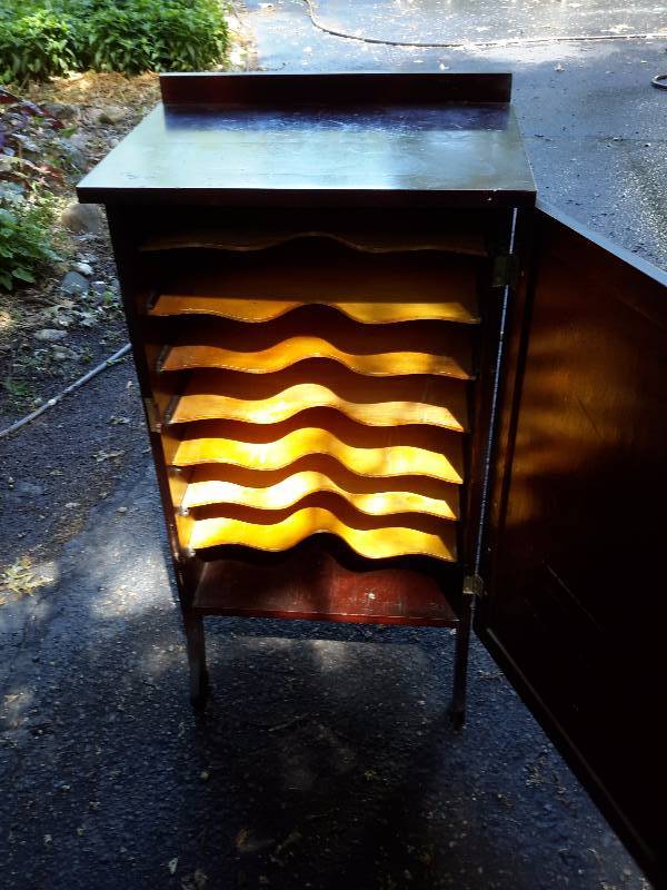 Very old record cabinet.. 7 record slots.. 22in x 19 12 in x 37 12 in h.. Looks like OAK wood.. DARK STAINED