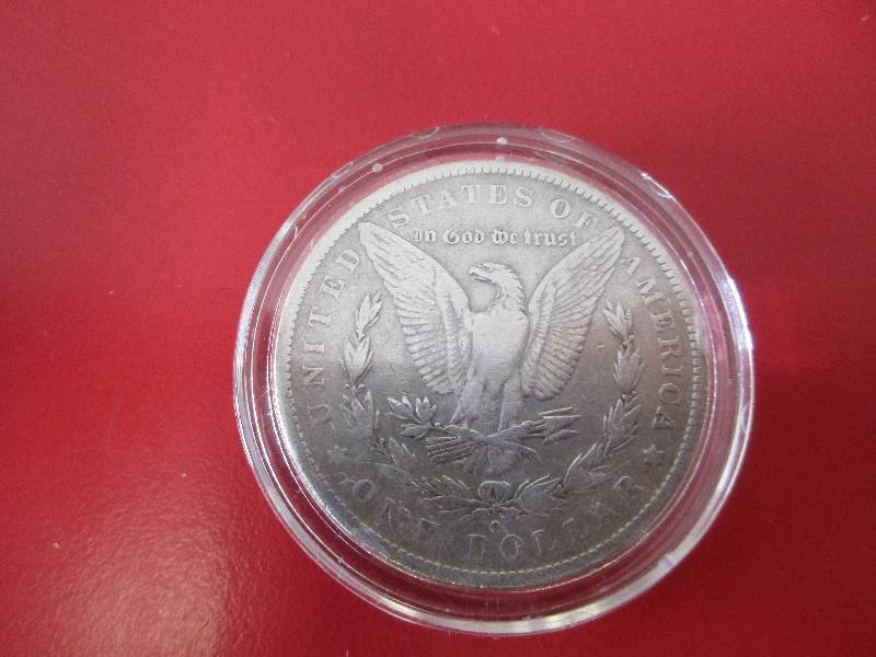 1883-O Morgan Silver Dollar in protective capsule.  The capsule can be easily opened if the winning bidder wishes to transfer to a collection folder.