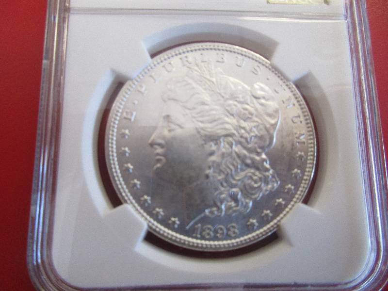 Lot #4 - 1898-P (Philadelphia) NGC Certified Morgan Silver Dollar in Mint State 62 grade. Beautiful 90% Silver coin with cartwheel effect and mint luster.
