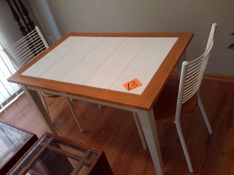Kitchen table with ceramic inlayed center and wood border.. A few of the ceramic inlays appear to be cracked, but such a fine crack has no bearing on the surface.  2 metal chairs with wood seats. Dim Table 46in x 30 in.