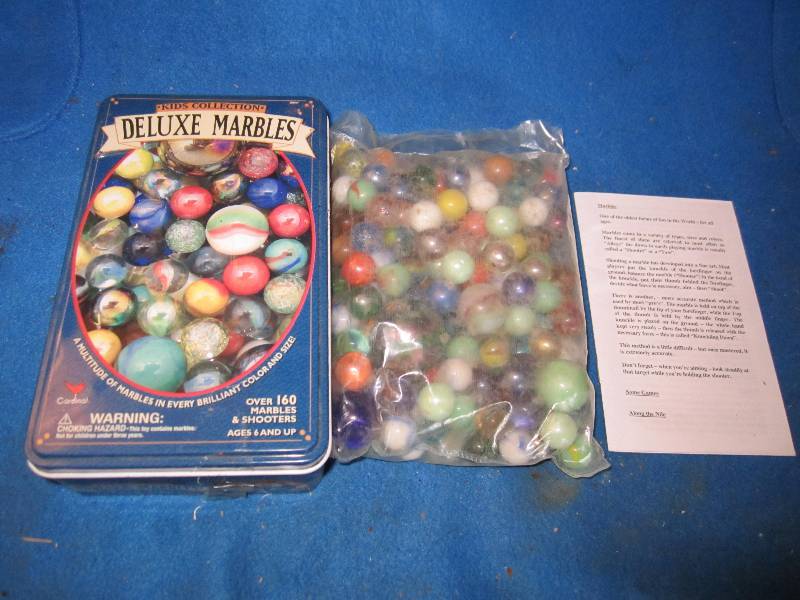 lot 73 image: Tin of marbles in unopened package...