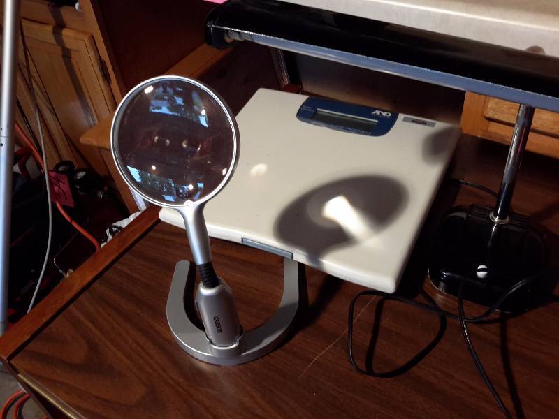 lot 105 image: Misc. Items  magnifying glass on stand, small crockpot casserole, Table lamp (bulb bad), Bathroom Scale, Portable light with siren