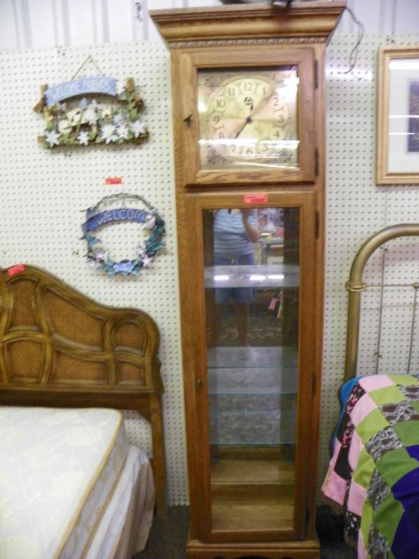 Curio cabinet with clock face, clock opens for additional cabinet space, note one lower glass panel is cracked and broken
