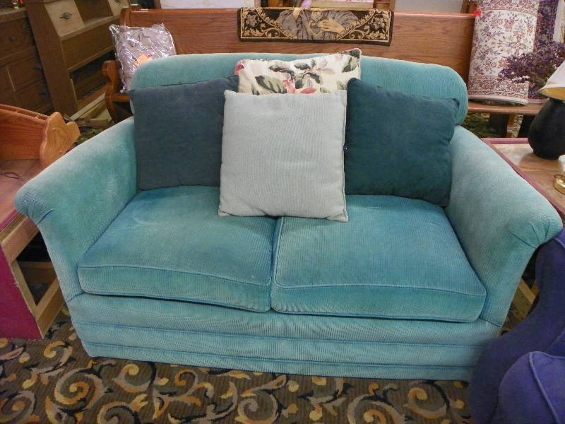 Turquoise love seat with pillows, faded