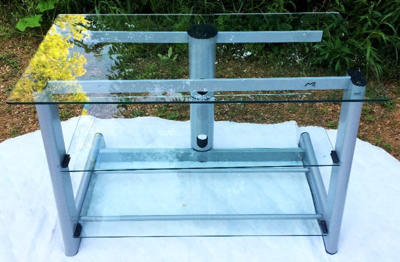 lot 1 image: High Quality Sleek Contemporary Styling BellO TV Entertainment Stand Retails $299.00 Excellent Condition Up To 52 Television Tempered Safety Glass & Heavy Duty Steel Frame Bonus Sleek Management Design Cable System That Hides Unsightly Wires & Cables