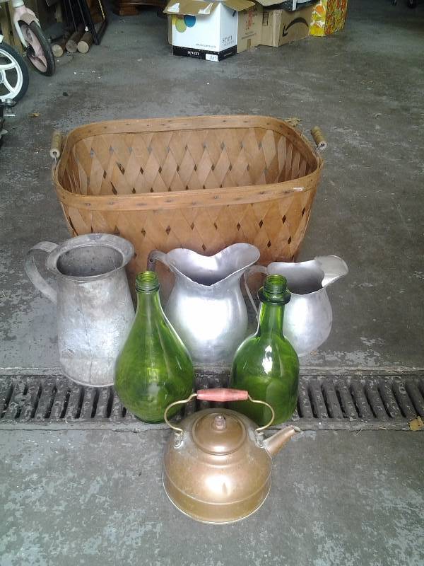 lot 19 image: Big Wicker Basket With 3-Aluminum Pitchers, 2-Green Glass Bottles, 1-Copper Tea Pot