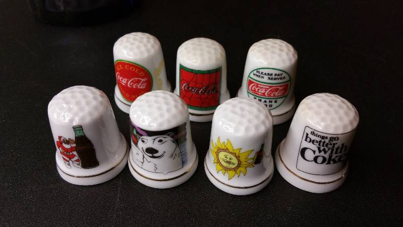 lot 27 image: Set of (7) Porcelain Coca-Cola Thimbles