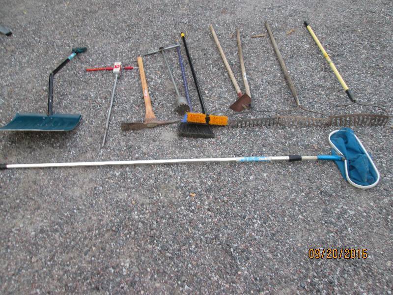 lot 130 image: 3 steel rakes , 1 hoe, 2 small brooms, 1 pick axe, 1 snow shovel, 1 yard rake missing 2 teeth, 1 shop broom, 1 minnow net and 1 gopher tool
