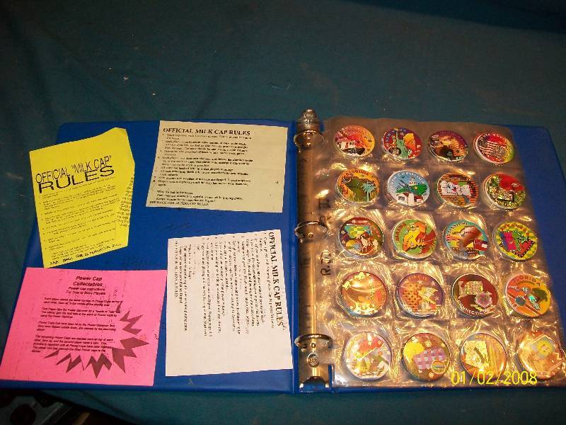 lot 54 image: 100 Vintage Pogs in Clear Plastic Double Sided pages with Individual Slots in Blue Ring Binder.