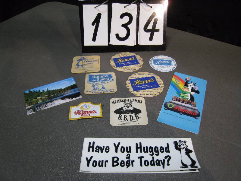 lot 134 image: Group of Hamms Beer items including coasters, patch, bumper sticker, post card and table tent, some with Sasha the Bear