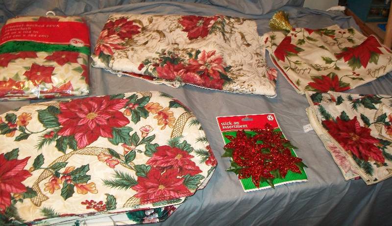 lot 127 image: Lot of Poinsettia Decorated Holiday Items 2-Table Cloths, 11- Place mats, Runner, Stick-Ons
