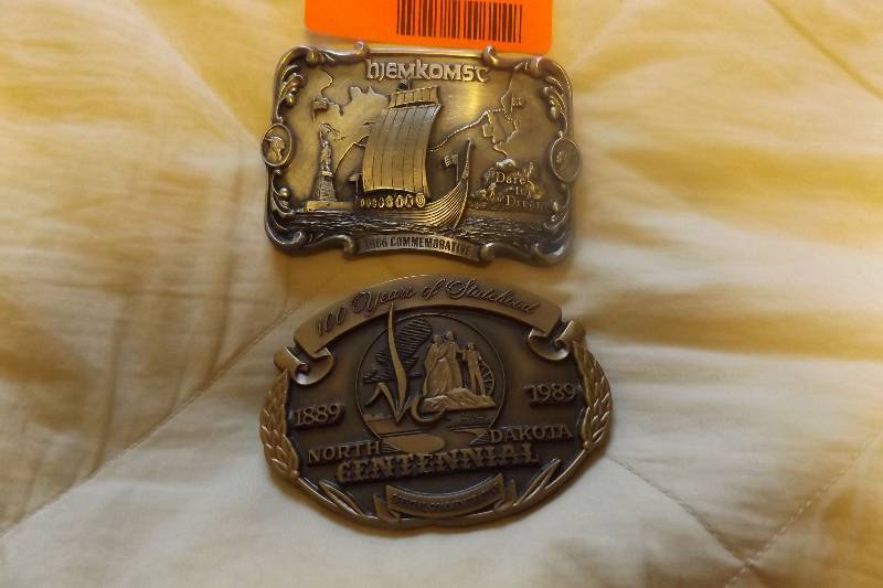 lot 187 image: Two belt buckles, Hjemkomst commerative, North Dakota Centennial