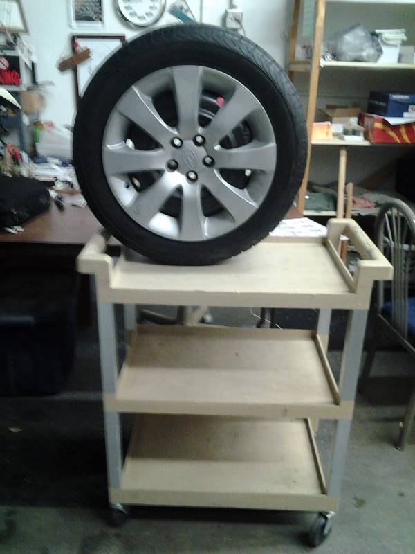 lot 30 image: Rubbermaid Rolling Cart, Subaru Rim With Tire (Like New) 205-55-R16