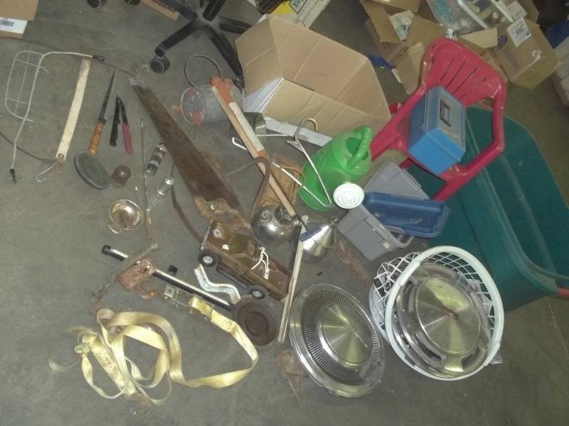 lot 77 image: Water can, strap, hand saw, kitchen knives, red kids plastic chair, Oldsmobile hubcaps, blue tackle box, vintage sprayer, cream separator cups, green tote, splitting wedge, terminal brush