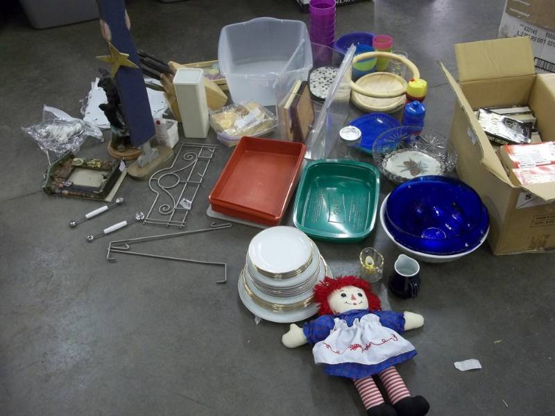 lot 91 image: Raggedy Ann doll, plates, syrup serving cups, serving bowls, assorted Tupperware, bear dcor, candles, knife block with knives, popcorn bowls, includes box of books