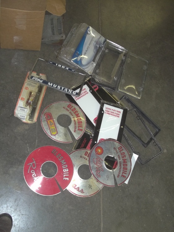 lot 101 image: 1964 Ford Mustang license plate frame, other license plate frames and protectors, Oldsmobile Cutlass sign