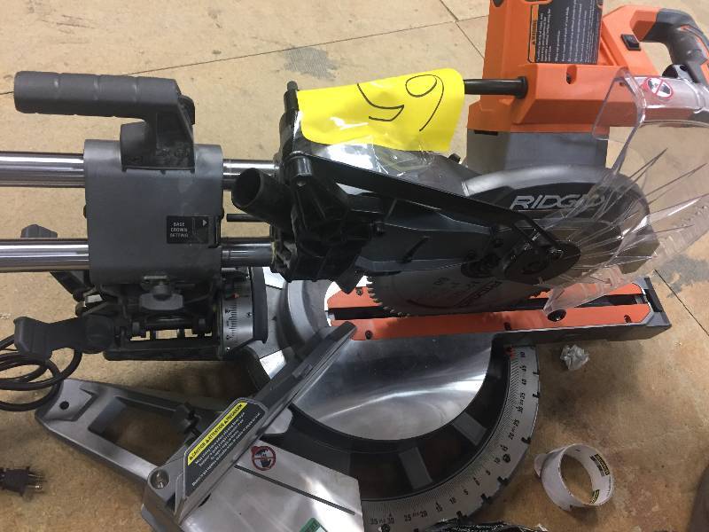 lot 65 image: RIDGID 15 Amp 12 in. Corded Dual Bevel Sliding Miter Saw with 70 Degree Miter Capacity Model#  R4221  Small crack see pictures, turns on and runs
