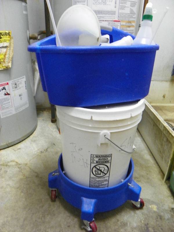 Partial pail of sidewalk salt, wheel base, tote with spray bottles