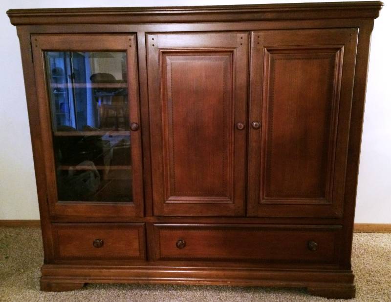lot 224 image: Striking Refined Elegance Solid Wood Media Console Entertainment Cabinet With Smoke Glass Doors & Beautiful Accents Wood Doors Tuck Away Into Unit With Slide Out TV Tray - 25x62x53 - Excellent Condition