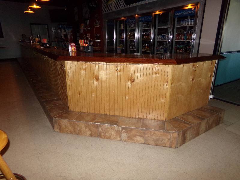 lot 184 image: BAR, 42 tall, 27 2 long on one side, 5 angle piece and 44 long on the short side. Will need to be removed, DOES NOT INCLUDE THE LIQUOR or other items sitting on or under the bar.