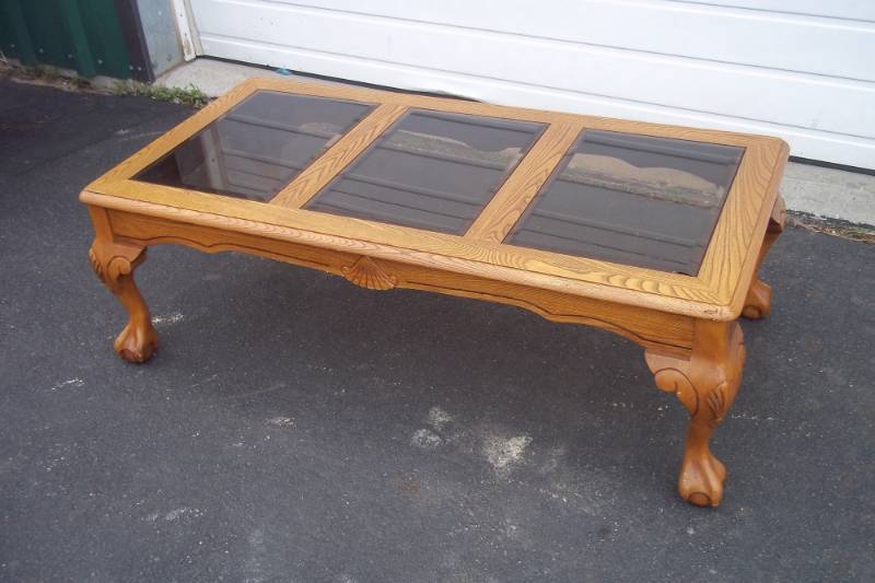 lot 118 image: Solid oak claw feet coffee table with smoked glass. One glass has a chip.  50 long.