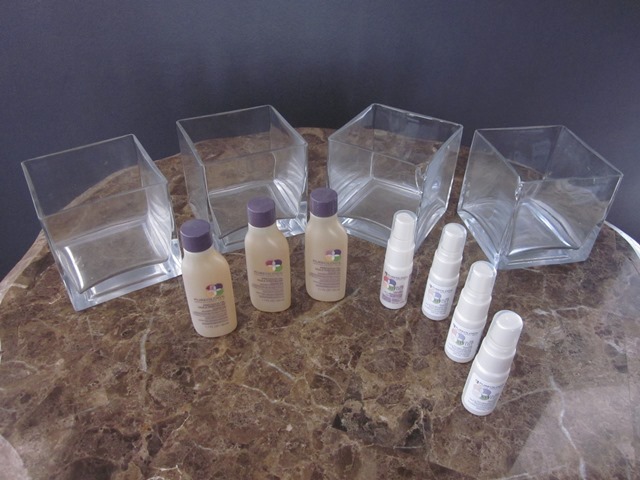 lot 81 image: Four Glass Square Display Containers (two with cracks in corners (see photo) and Pureology Precious Oil (3 1.7 oz.), Fortifying Heat Spray (1 .5 oz.) and Radiance Amplifier (3 .5 oz.)