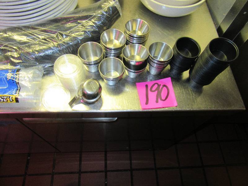 lot 190 image: Approx 55 stainless  2 oz sauce containers.. Sleeve of plastic with a few lids