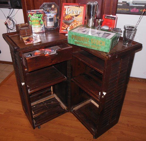 lot 96 image: Liquor Cabinet with Professional Bar Set, Drink Assist, Bartenders Guide, New SEALED Cooking With Beer Cookbook, A Guy Goes Into A Bar, Coaster Set, and Measured Bottle Tops