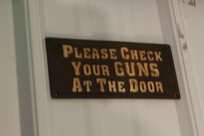 lot 256 image: Please Check Your Guns At The Door Sign
