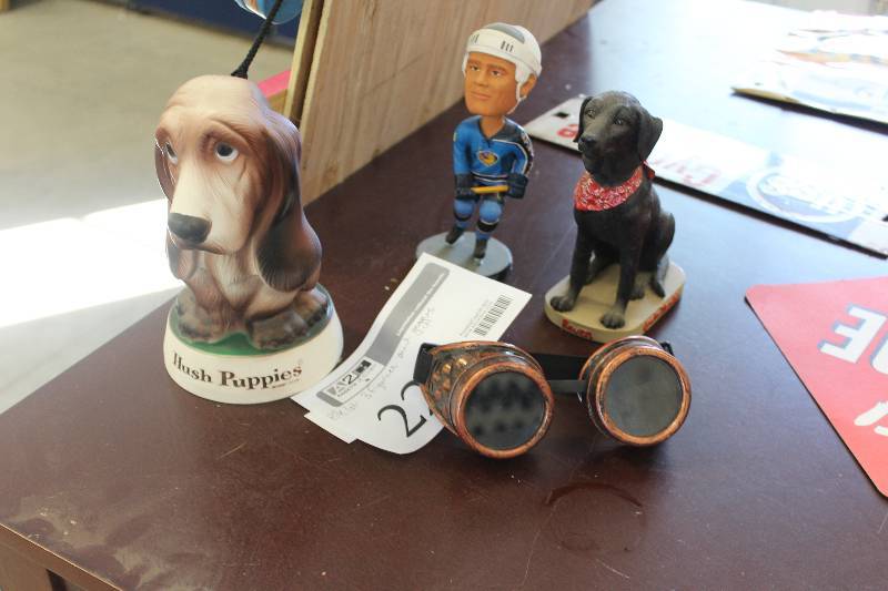 lot 221 image: Lot of (4) Hush Puppies Dog Figurine, Black Lab Dog Figurine, Bobby Holik Bobblehead, Welding Goggles