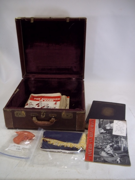 lot 175 image: Vintage Accordion Case with music, vintage squirt gun, American Rifleman Magazine and 1924 Cornhuskers book