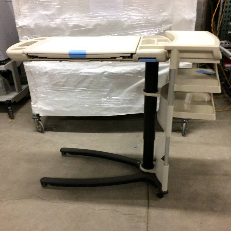 lot 7 image: Retails New $1400 Hill-Rom Art of Care Overbed Table 636 Hospital Mobile Bed Side Expandable Tray Table - Great Condition - 1st Picture Is A Stock Photo - White Surface Top - Does Not Include Side Dispensers Or Vanity