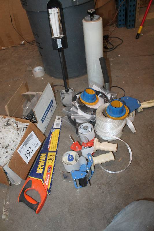 lot 192 image: Packing Supply Lot - Including (2) Tape Guns Irwin Hand Saw (1) Partial roll of Shrink wrap with Holder (2) Boxes of Peg Board Hooks Partial Roll of Banding Strap