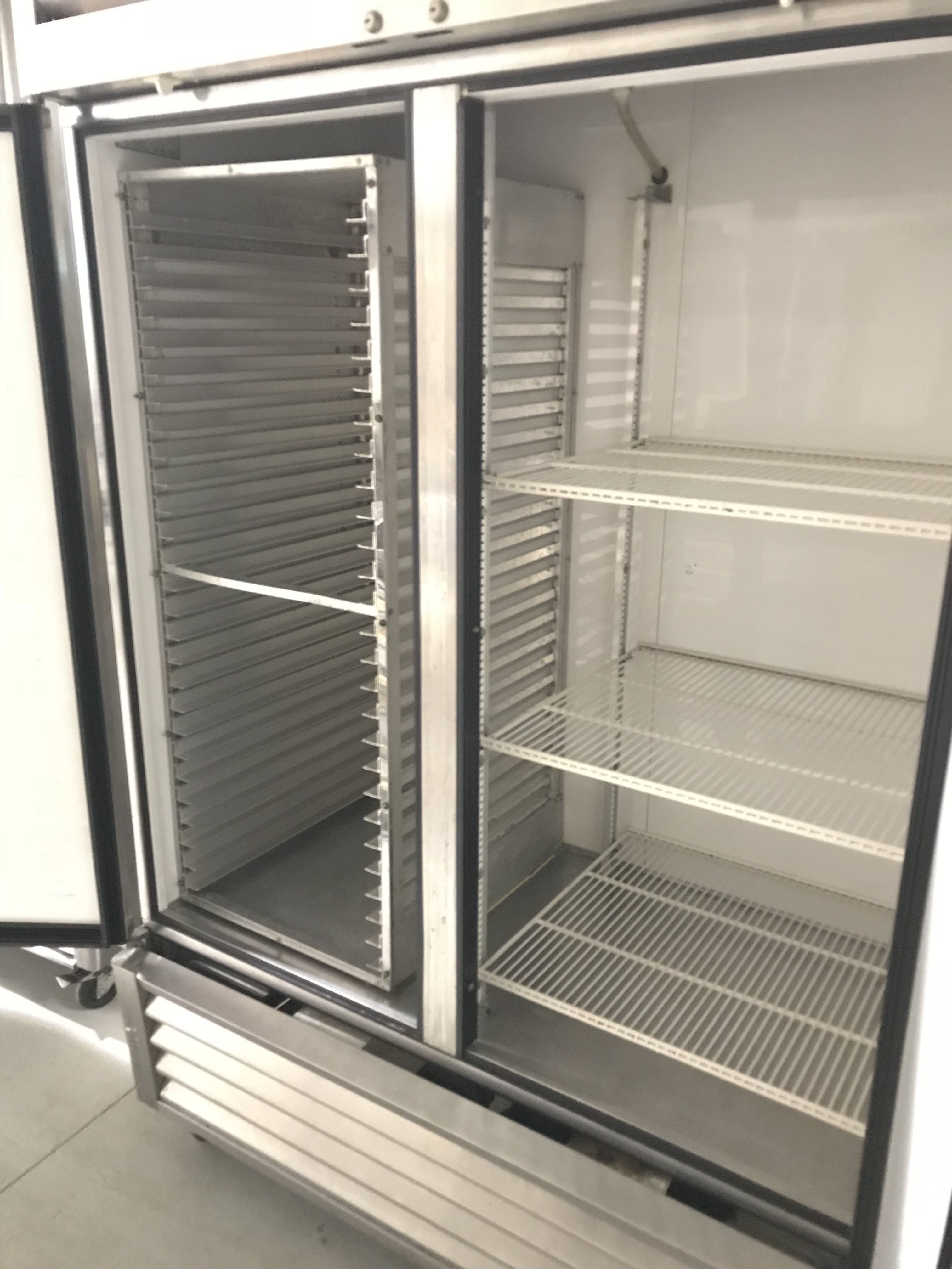 lot 18 image: True Double door stainless fridge on wheels. Runs Cools