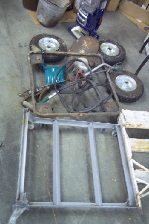 lot 57 image: Jumper cables, 2 rolling flat carts, vintage ladder, 3 wheel barrow wheels, garden hose holder, watering sprayer, shovel, vacuum, step stool