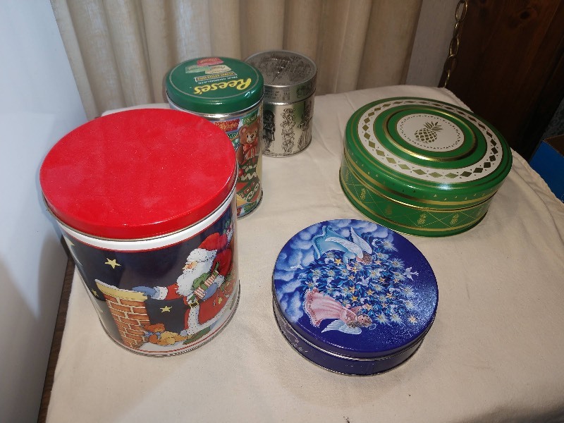 lot 99 image: Santa Delivering Presents Tin, Green Reeses Milk Chocolate Peanut Butter Cups Tin, Silver-Tone E. Otto Schmidt Embossed Gingerbread Tin, Shades of Blue Angels and Christmas Tree Tin, Vintage Green and Gold Pineapple Tin w Embossed Domed Lid