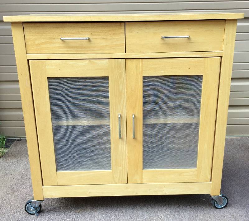 lot 12 image: Heavy Duty Natural Oak Rolling Mobile Kitchen Island Cabinet With Screen Doors (Can Be Changed To Glass If You Want) & Locking Wheels - Great Condition