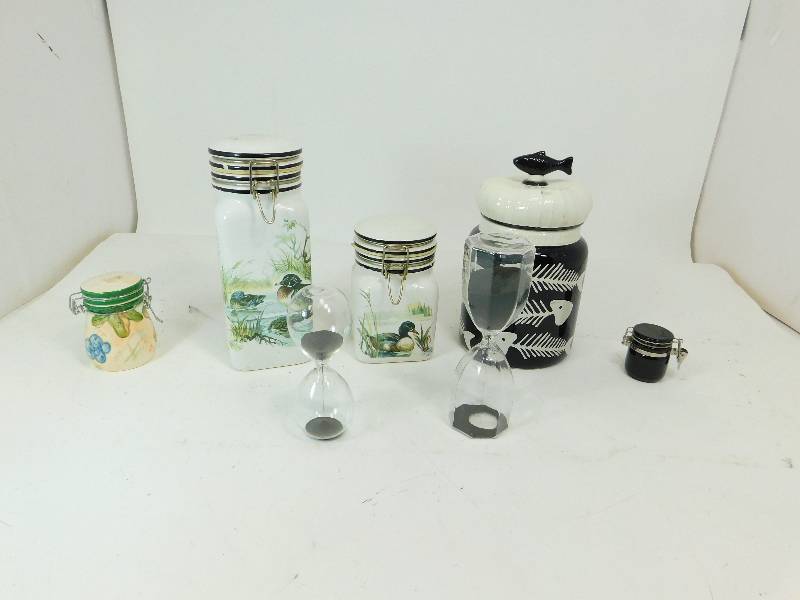 lot 45 image: Five Different Size Glass Containers With Lids & Two Sand Containers Hour Glasses