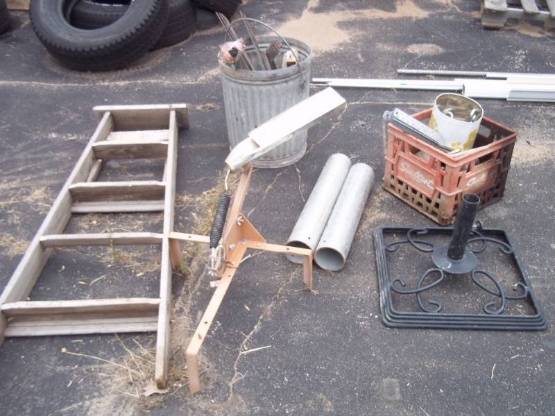lot 142 image: Milk Crate wMisc. Wheels, 2 Galvanized Pipes, Clay Pigeon Thrower, Umbrella Stand, Metal Can wMisc. Rebar & Brackets, Wood Ladder