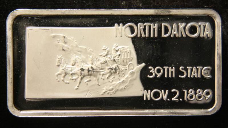 lot 46 image: 1 TROY OZ. .999 FINE SILVER BAR 50 STATES SERIES NORTH DAKOTA (NICELY TONED)