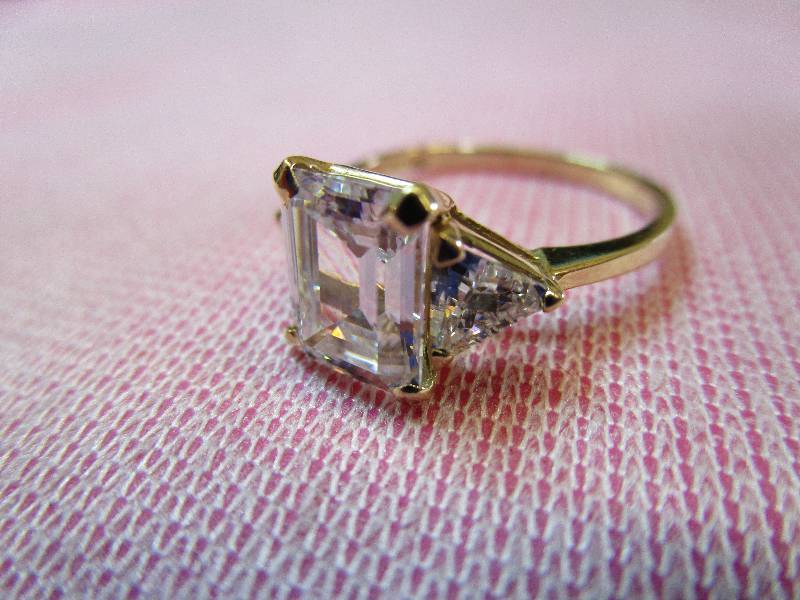lot 141 image: 14K YELLOW GOLD SIZE 6 CZ DIAMONIQUE EMERALDTRILLION CUT RING, 2.5 GRAMS.