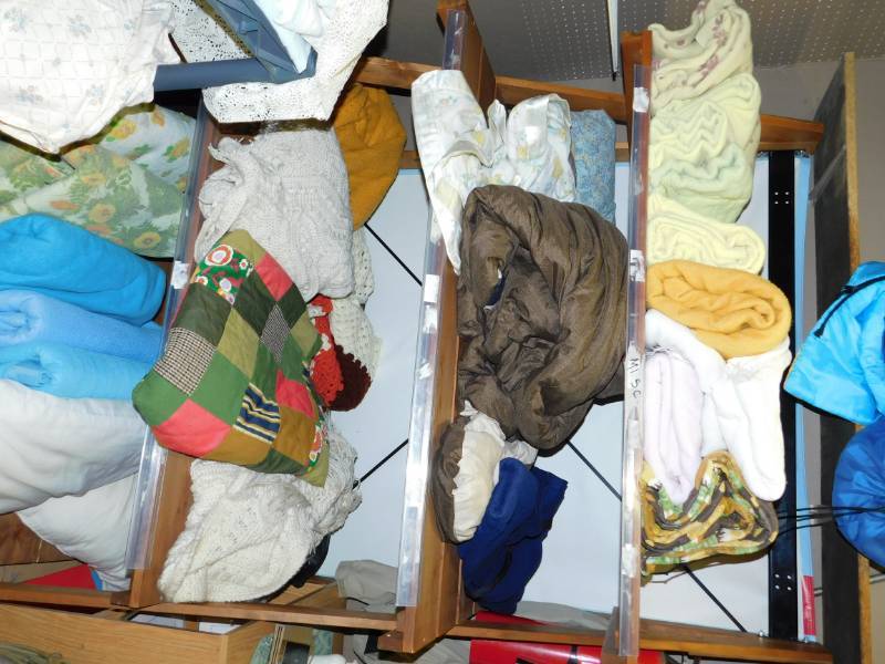 lot 117 image: Shelving Unit With Contents---BlanketsQuiltsSleeping BagsFamily Picture Of Baby Jesus-Mary & Joseph