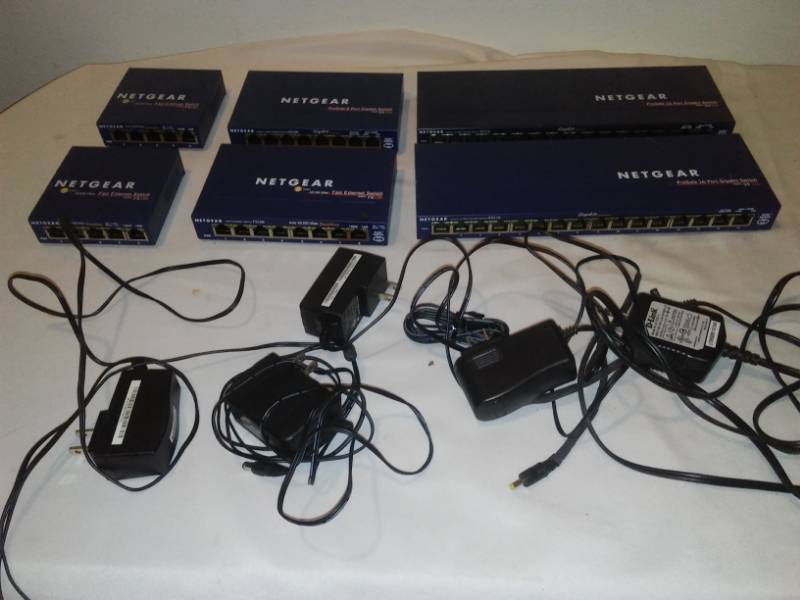 lot 186 image: 6 Netgear ethernet switches and power cords.
